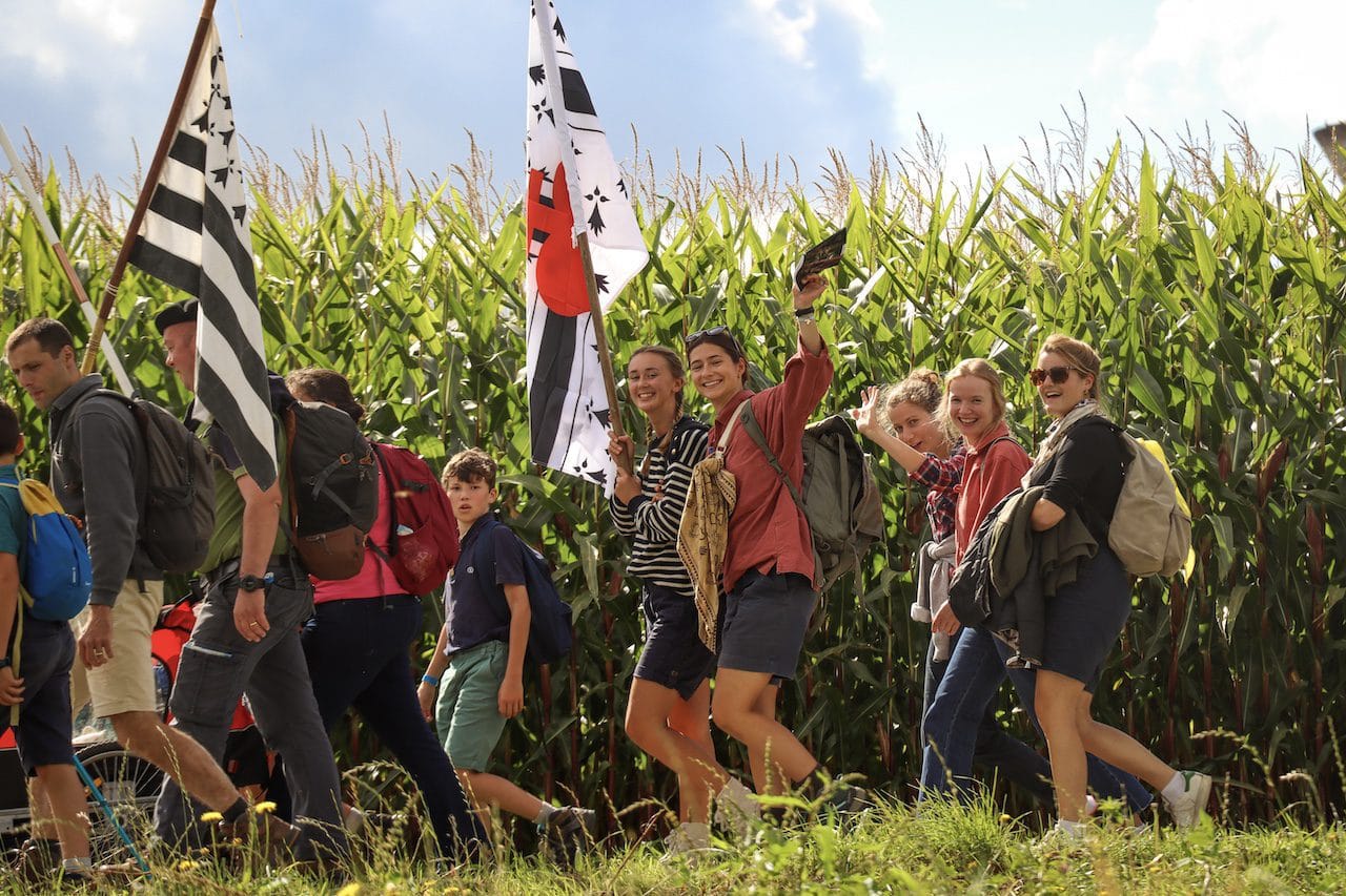 En gruppe pilegrimer langs et jorde med maisplanter.