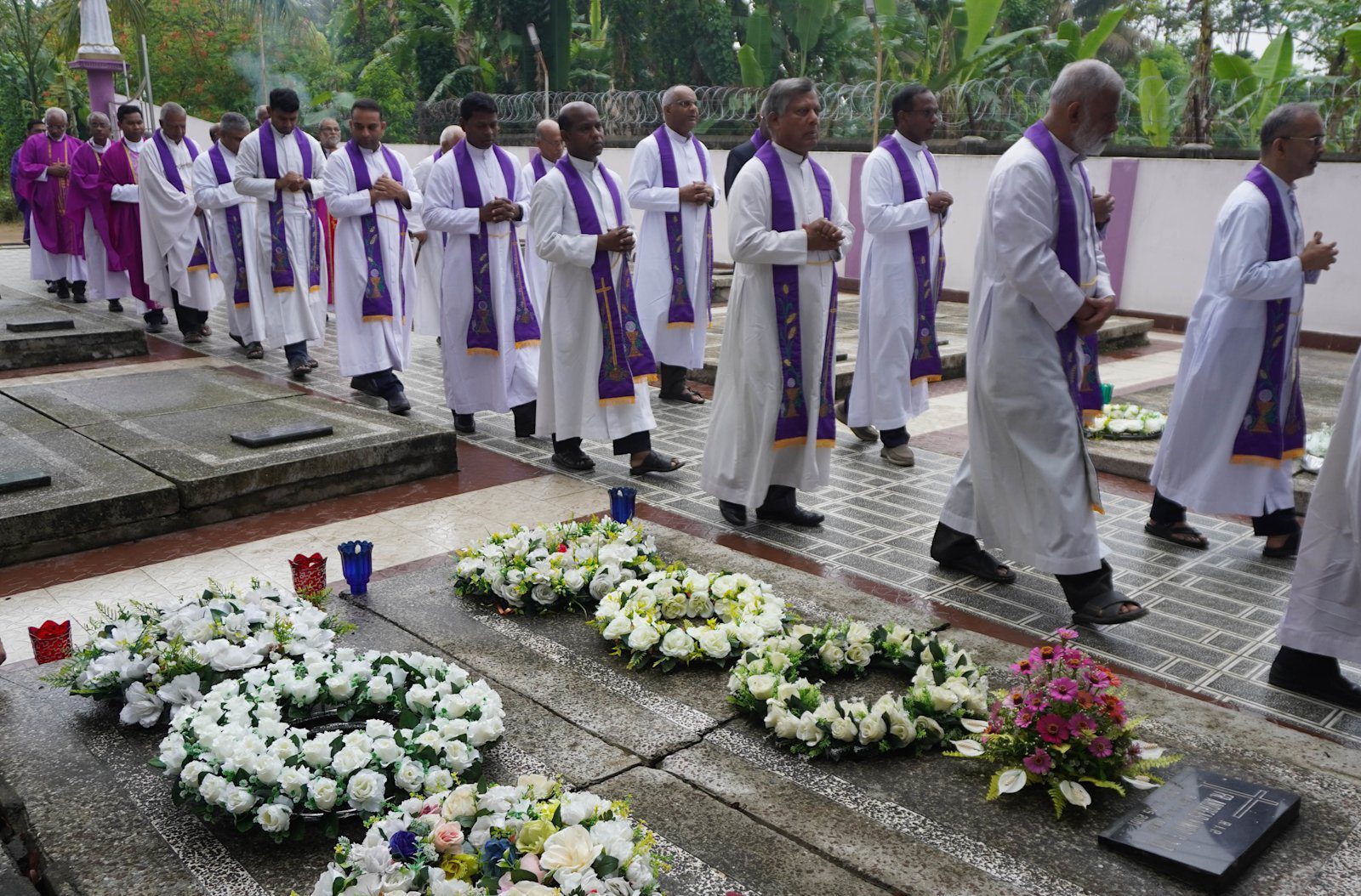 Salesianerprester ber ved gravene til tre medbrødre drept i Manipur i 2001 under minnemessen i Dimapur 15. mai 2026.