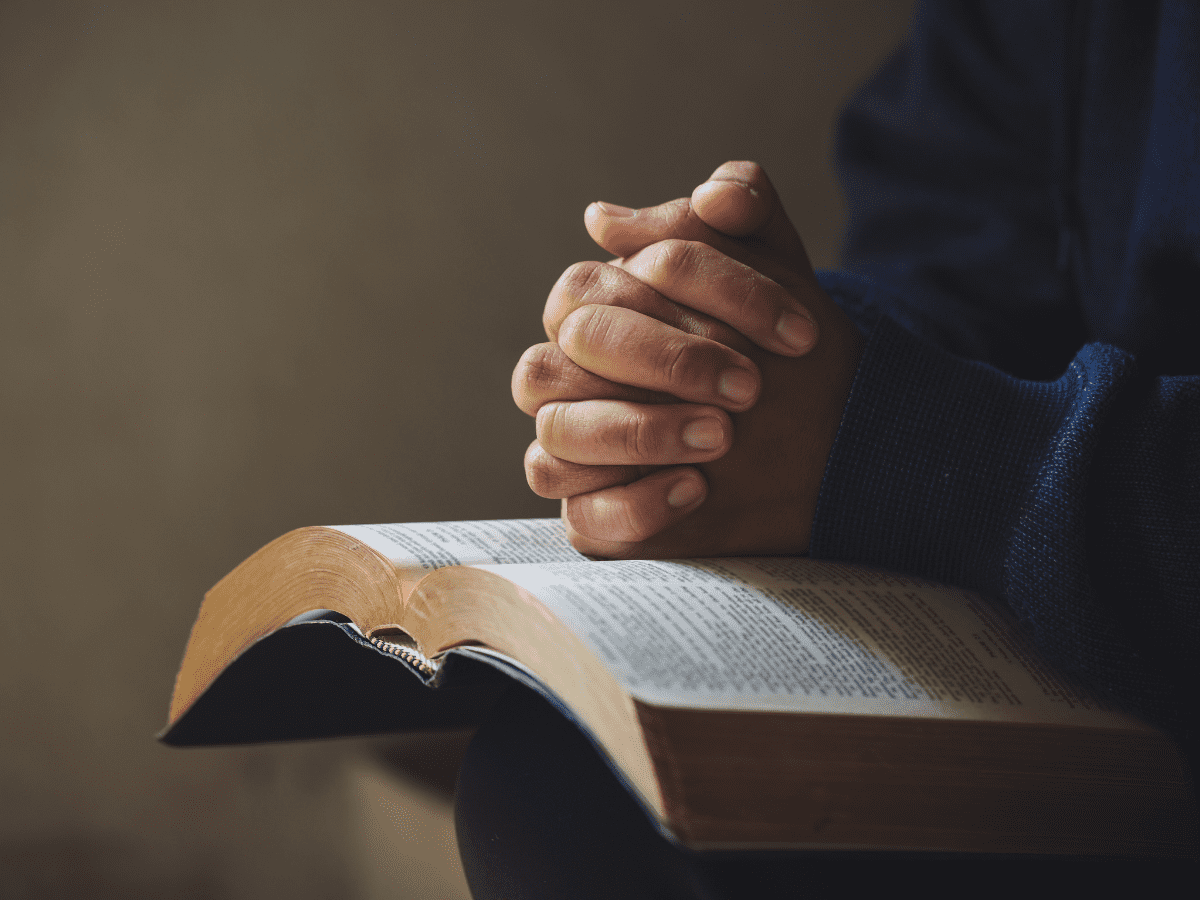 Foldete hender på en Bibel